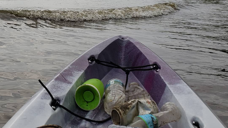 Litter being cleaned out of Four Mile Run in Alexandria, Va. by a kayaker